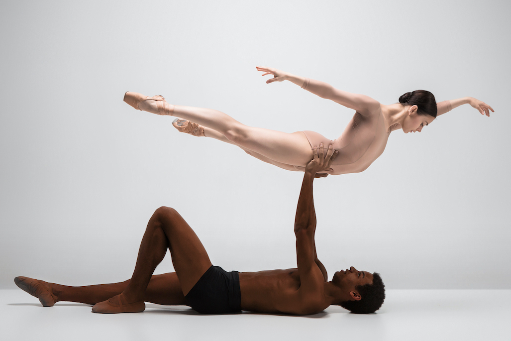 Couple of ballet dancers dancing over gray background