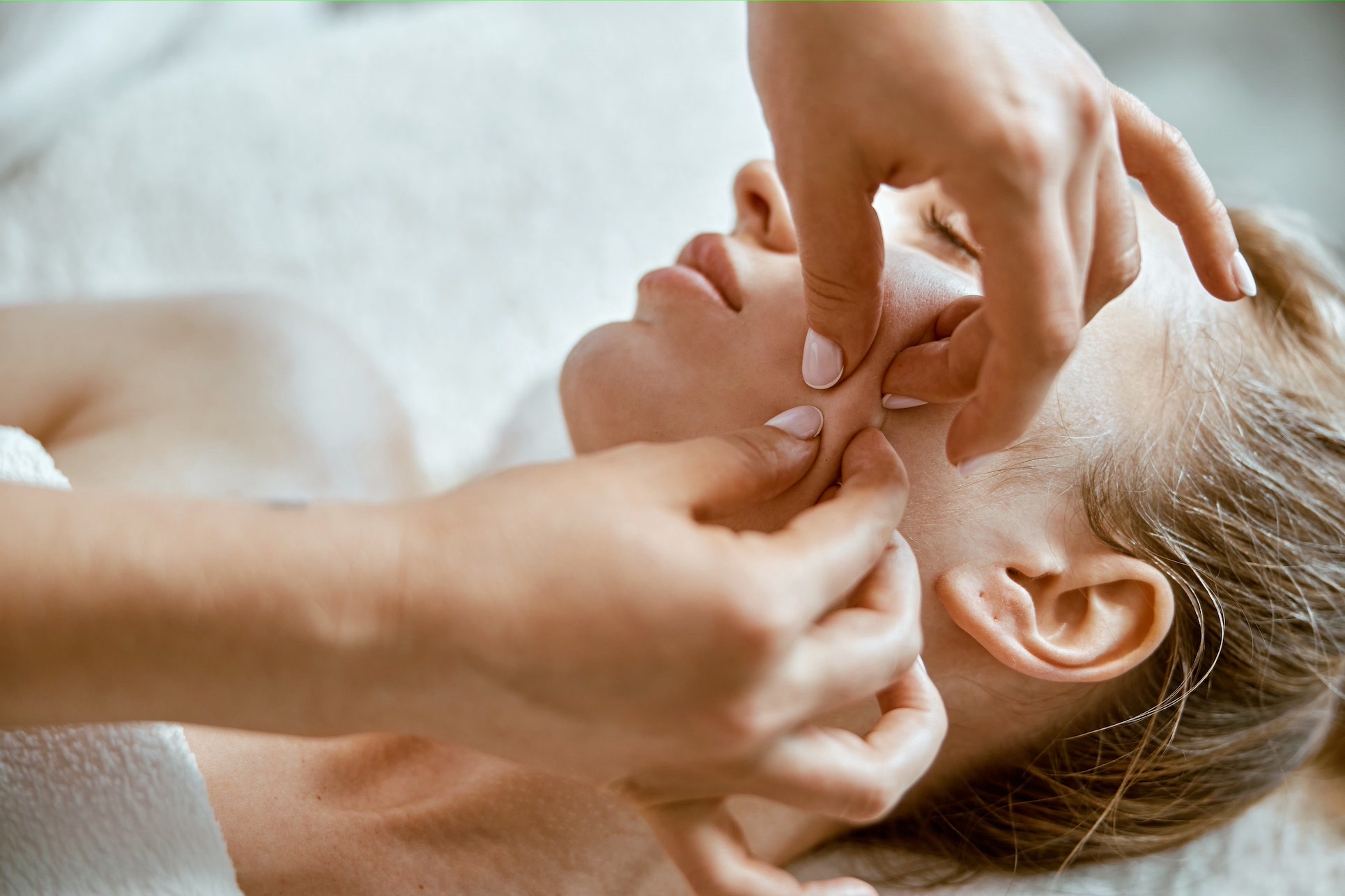 Therapist is doing face relaxing massage to a young woman in modern wellness cabinet