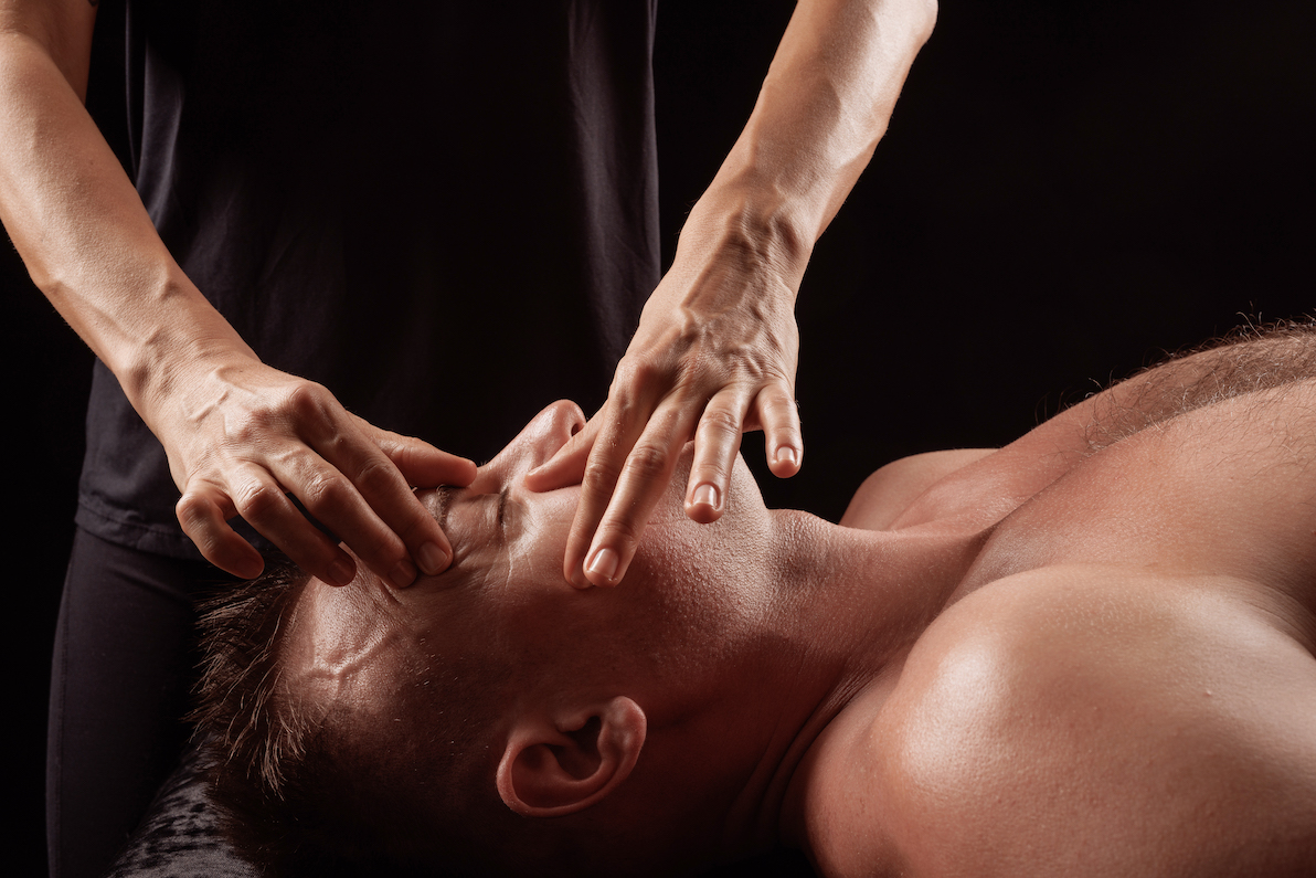 Facial massage therapy session for a man, therapist applying pressure points around eyes and temples in spa.