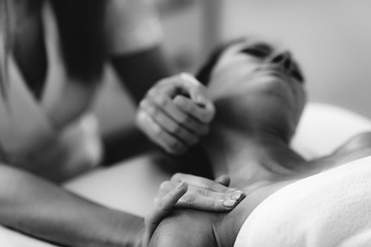 Physiotherapist massaging female patient with injured neck. Sports injury treatment.