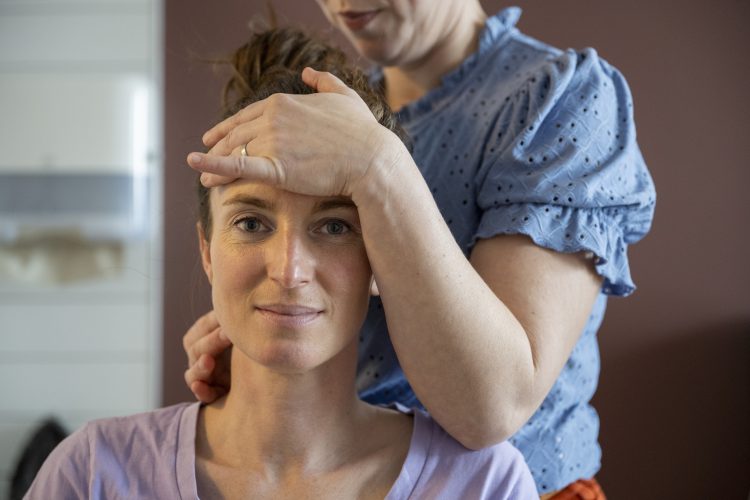 Woman giving another woman a head massage.